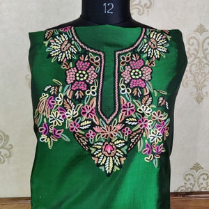 May include: A green silk kurta with a floral embroidery design. The embroidery is in shades of pink, white, and yellow.