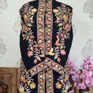 May include: A black long-sleeved jacket with intricate floral embroidery in shades of orange, yellow, and pink. The jacket has a mandarin collar and a button closure.