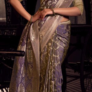 May include: A luxurious purple and gold sari with intricate paisley patterns. The sari features a detailed gold border and is draped elegantly. The image showcases the rich texture and design of the traditional Indian garment.