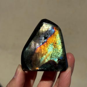 May include: A dark gray labradorite crystal with iridescent rainbow colors, including blue, green, orange, and yellow.