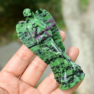 May include: Green and black gemstone angel figurine carved from natural stone. The angel has a detailed design and is a beautiful piece of art.