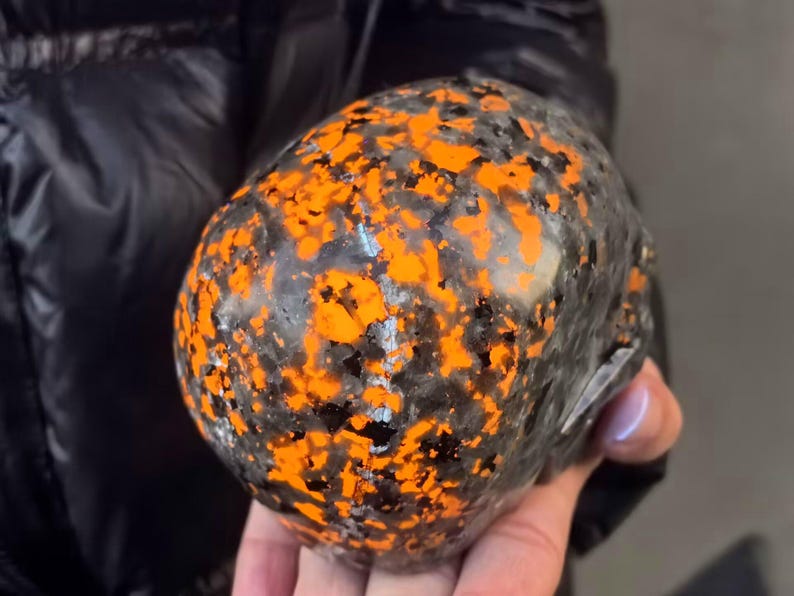 May include: A black and orange skull-shaped object with a speckled pattern. The object is made of a smooth, hard material.
