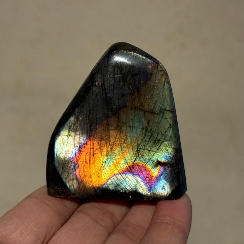 May include: A dark gray labradorite crystal with iridescent rainbow colors, including orange, yellow, green, blue, and purple.