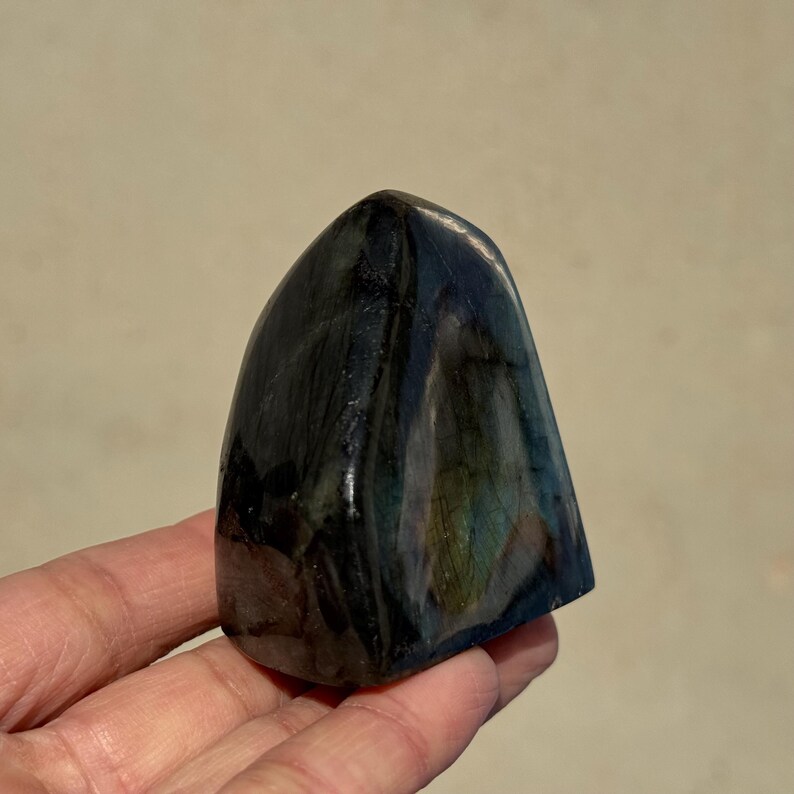 May include: A dark blue and green labradorite crystal freeform, polished to a smooth finish. The crystal has a unique iridescent sheen.