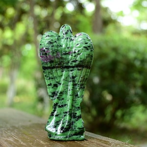 May include: Green and black gemstone angel figurine with wings. The angel is carved from a green stone with black and pink streaks.