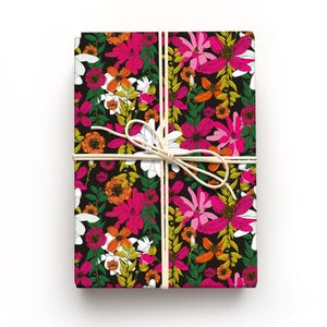 May include: A wrapped gift with a floral design. The wrapping paper has a black background with a vibrant pattern of pink, orange, white, and yellow flowers. The gift is tied with natural twine.