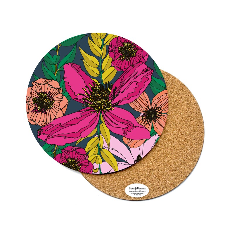 May include: Round cork coaster with a floral design featuring pink, yellow, and green flowers on a dark blue background. The coaster has a cork backing.