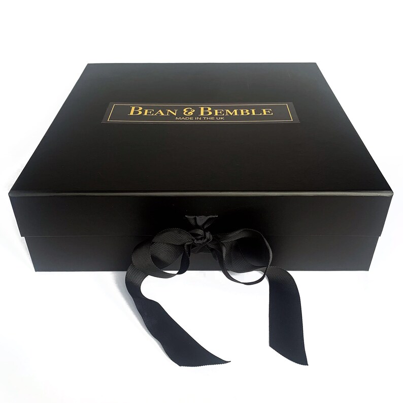 May include: A black gift box with a black ribbon tied in a bow. The box has a gold label that says "Bean & Bemble Made in the UK."