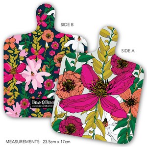 May include: Double-sided cutting board with a floral design. One side features a dark blue background with pink, white, and orange flowers. The other side has a white background with pink, orange, and yellow flowers. The board measures 23.5 inches by 17 inches. The text "Bean & Bembi" and "www.beanandbembi.com" is printed on the board.