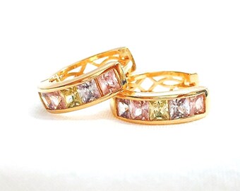 May include: A pair of gold hoop earrings with a row of colorful square-shaped gemstones. The gemstones are pink, yellow, and clear.