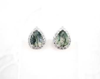 May include: A pair of silver earrings with green agate pear-shaped stones set in a halo of clear cubic zirconia.