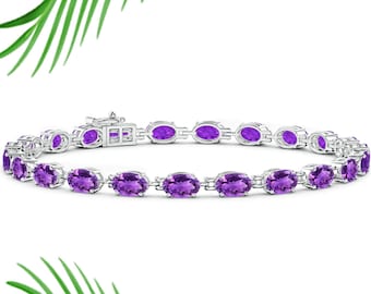 May include: A silver bracelet featuring oval-cut, vibrant purple gemstones. The gemstones are set in individual links, creating a flexible and elegant design. The bracelet has a secure clasp.