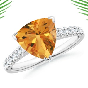 Könnte beinhalten: Ein silberner Ring mit einem dreieckigen orangefarbenen Edelstein und einer Reihe kleiner Diamanten.