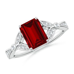 May include: A silver ring with a large, red, emerald-cut gemstone surrounded by smaller, clear gemstones in a floral design.