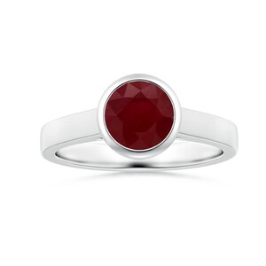 May include: A silver ring with a large, round, deep red ruby gemstone. The ruby is set in a bezel setting, and the band is a simple, polished silver. The ring is displayed against a white background.