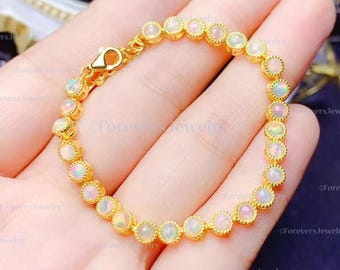 May include: A gold bracelet with a row of white opal stones. The bracelet has a clasp closure.