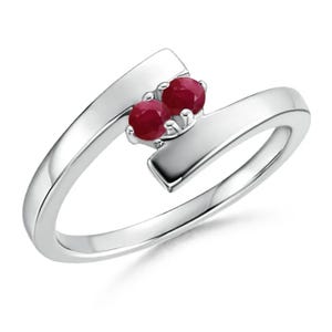 Può includere: Un anello d'argento dal design moderno, con due gemme rotonde di colore rosso intenso. La fascia dell'anello è elegantemente curva, con le gemme incastonate su una piattaforma rettangolare.