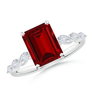 May include: A silver ring featuring a large, rectangular, deep red gemstone as the focal point. The band is adorned with smaller, round, clear gemstones. The ring is set against a white background, highlighting the sparkle of the gems.