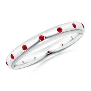 May include: A thin silver band with a row of small red gemstones set into the metal. The ring is a simple and elegant design.