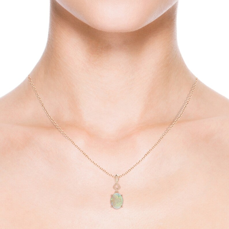 May include: A delicate gold chain necklace with a pendant featuring a green opal gemstone.