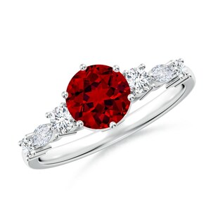 May include: A silver ring with a red gemstone surrounded by smaller white gemstones.