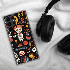May include: A black phone case with a colourful Day of the Dead design. The case features skeletons, flowers, and other festive elements.