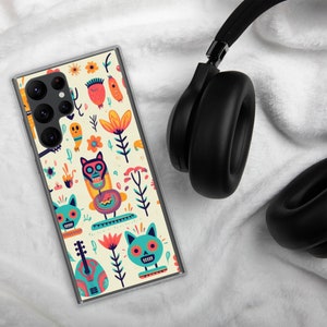 Könnte beinhalten: Eine transparente Handyhülle mit einem farbenfrohen Design mit Totenköpfen, Blumen und Musikinstrumenten. Die Hülle ist für ein Samsung Galaxy S22 Ultra Handy konzipiert.