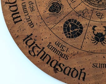 May include: A circular brown cork board featuring a laser-engraved wheel of the year design. The surface displays black text including Mabon, Lammas, and various zodiac symbols, alongside a central tree illustration and Celtic knot motifs.