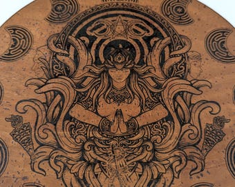 May include: A circular cork coaster featuring a dark laser-engraved illustration of a central figure with hands pressed together in prayer, surrounded by intricate swirling foliage, torches, and crescent moon symbols arranged in a circular border.