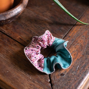May include: A teal and pink fabric scrunchie with a white and red geometric pattern.