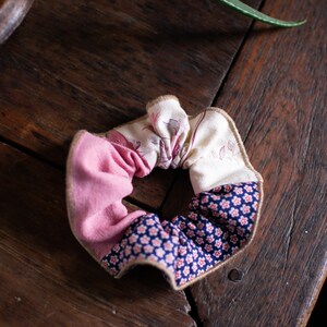 May include: A pink, white, and blue fabric scrunchie with a floral pattern.