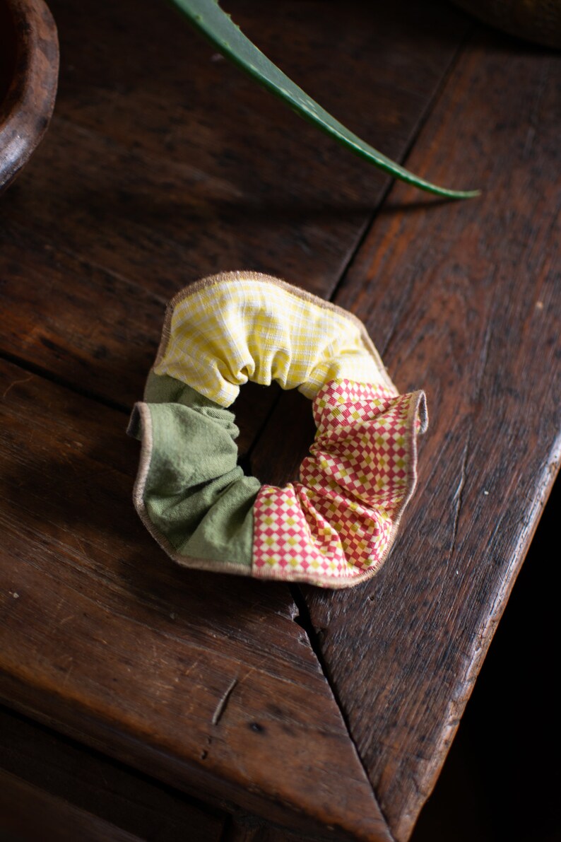 May include: A handmade fabric hair scrunchie with a yellow and white checkered pattern, a green fabric section, and a red and white checkered pattern.