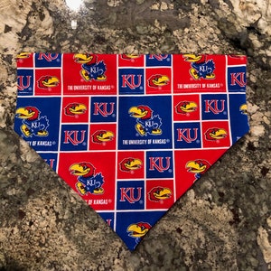 May include: A blue and red bandana with a repeating pattern of the University of Kansas Jayhawk mascot and the words "KU" and "The University of Kansas".