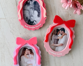 May include: Three oval-shaped photo frames in pink and lavender with bow accents. Each frame holds a black and white photo and features text: "Best Friends Forever", "Endless Love", and "Valentine's Day 2020".