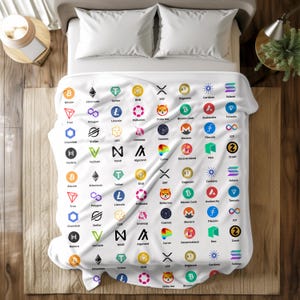 May include: White blanket featuring a repeating pattern of cryptocurrency logos, including Bitcoin, Ethereum, and Dogecoin. The blanket is spread across a bed with white pillows and a wooden nightstand.