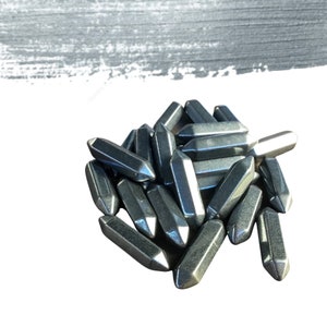 May include: A pile of silver-colored metal nail heads, some with a pointed tip and some with a flat tip.