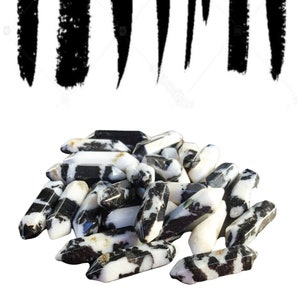 May include: A pile of black and white zebra jasper points. The points are smooth and polished, with a variety of shapes and sizes.