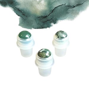 May include: Three roll-on bottles with gemstone tops. The gemstones are various shades of green and white. The bottles have clear plastic bases and white plastic collars. A watercolour wash in shades of green and grey is in the background.