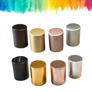 Può includere: Otto tappi per bottiglie cilindrici in varie finiture metalliche, tra cui nero, oro, bronzo e argento. I tappi sono disposti in due file, ciascuna con quattro pezzi. Le cime sono piatte e i lati lisci.