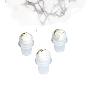 May include: Three clear plastic containers with white and brown spherical tops are arranged on a white background. The tops have a marbled appearance. The containers are cylindrical with a flared base.