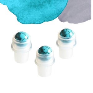 May include: Three turquoise rollerball applicators with a white base. The turquoise stones have dark veining. The applicators are set against a white background with teal and grey watercolour accents.