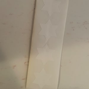 Puede incluir: Una hoja de pegatinas blancas con cuatro estrellas de seis puntas.