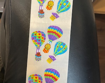 May include: A sheet of stickers featuring colorful hot air balloons with animal characters. The balloons are decorated with hearts, stars, and stripes. The stickers are perfect for adding a whimsical touch to any project.