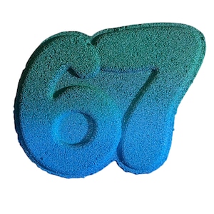 May include: A blue and green bath bomb in the shape of the number 67. The bath bomb has a textured surface and a gradient color scheme, transitioning from blue to green.