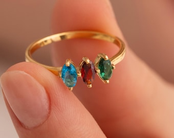 May include: A gold ring with three oval-shaped gemstones. The gemstones are blue, red, and green.