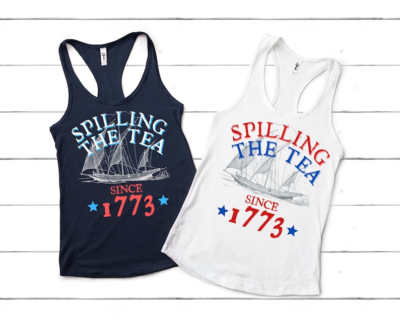 May include: Two tank tops in navy blue and white. Each tank top features a graphic of a ship with the text "SPILLING THE TEA SINCE 1773" in red, white and blue.
