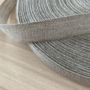 May include: A roll of gray woven ribbon. The ribbon is made of a natural fiber and has a textured surface.