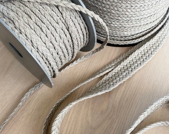 May include: Two spools of beige braided rope, one with a spool and one without. The rope is thick and has a woven texture.