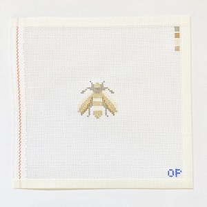 May include: A white canvas with a brown and yellow bee design. The canvas has a brown border and the letters "QF" in blue in the bottom right corner.