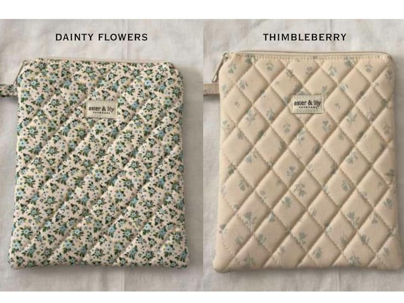 May include: Two rectangular quilted pouches with zips. The left pouch, labelled DAINTY FLOWERS, has a dense blue and green floral print. The right pouch, labelled THIMBLEBERRY, has a sparse floral print. Both feature an aster & lily label.